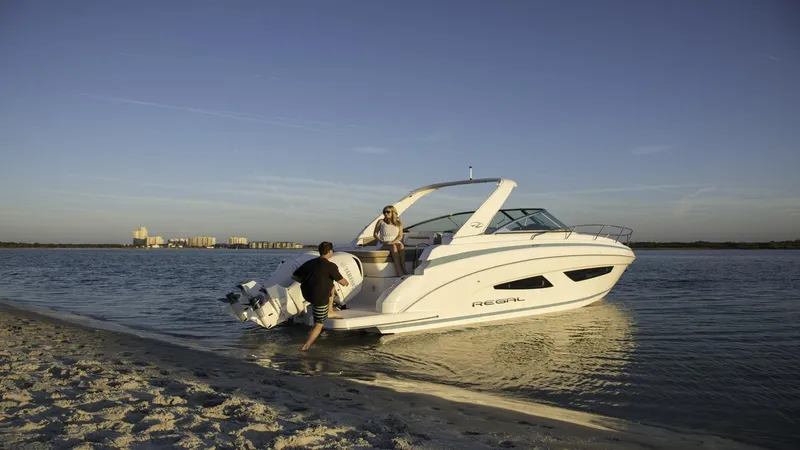 Slide: The Image of 2026 Regal 33 XO boat anchored near sandy beach at sunset. - 4