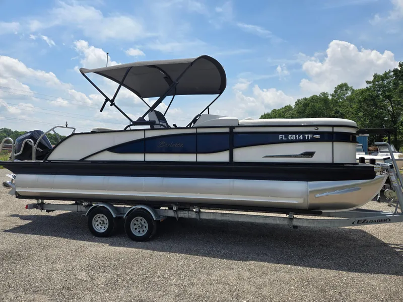Slide: The Image of 2022 Barletta Corsa 23U pontoon boat on trailer, parked outdoors under a clear sky. - 21
