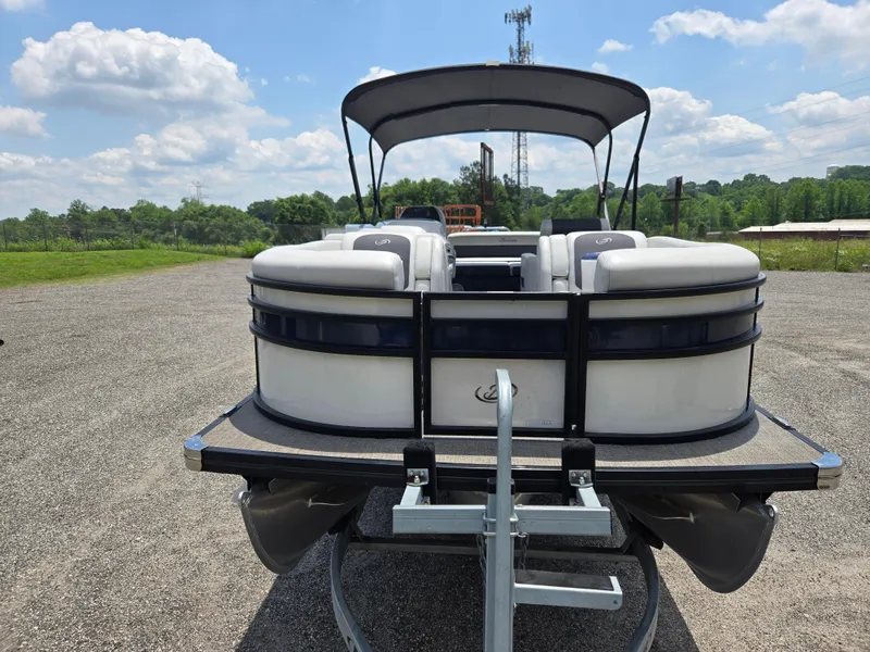 Slide: The Image of 2022 Barletta Corsa 23U pontoon boat on trailer, parked outdoors under a blue sky. - 23