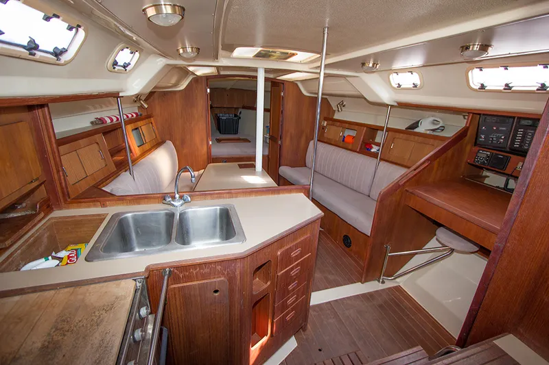 Slide: The Image of Interior of 1989 Hunter 37.5 sloop, featuring wood cabinetry, seating, and a compact kitchen area. - 8