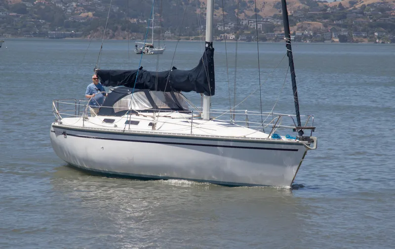 The Image of 1989 Hunter 37.5 sloop sailing on calm waters with a person at the helm. - 0