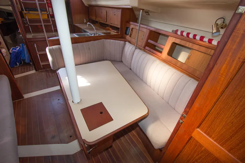 Slide: The Image of 1989 Hunter 37.5 sloop interior with dining area, wooden cabinetry, and cozy seating. - 11