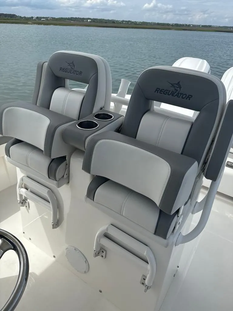 Slide: The Image of 2023 Regulator 28 boat seats with cup holders on a calm water background. - 12
