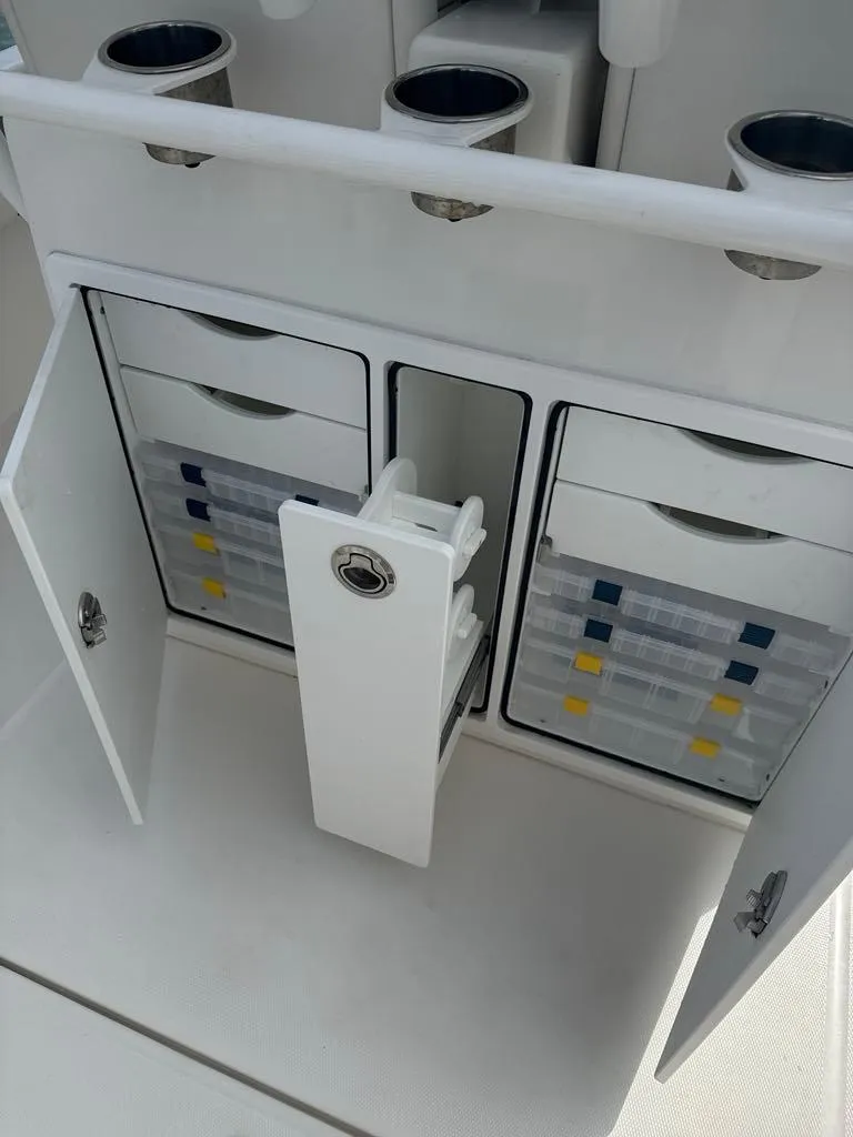 Slide: The Image of 2023 Regulator 28 boat storage compartments with organized tackle boxes and cup holders. - 16