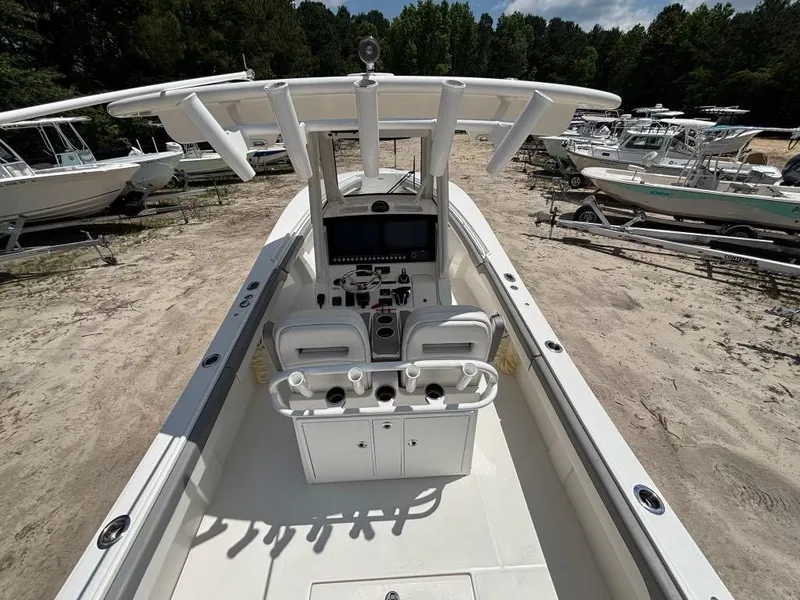 Slide: The Image of 2023 Regulator 28 boat with center console, docked on sandy shore, surrounded by trees and other boats. - 17