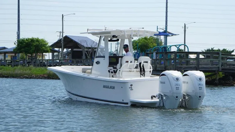 Slide: The Image of 2023 Regulator 28 boat with dual engines cruising near a dock. - 2