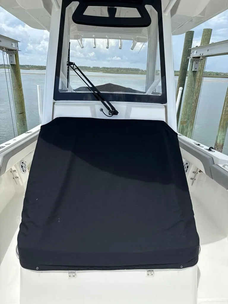 Slide: The Image of 2023 Regulator 28 boat with black cover, docked by the water. - 23