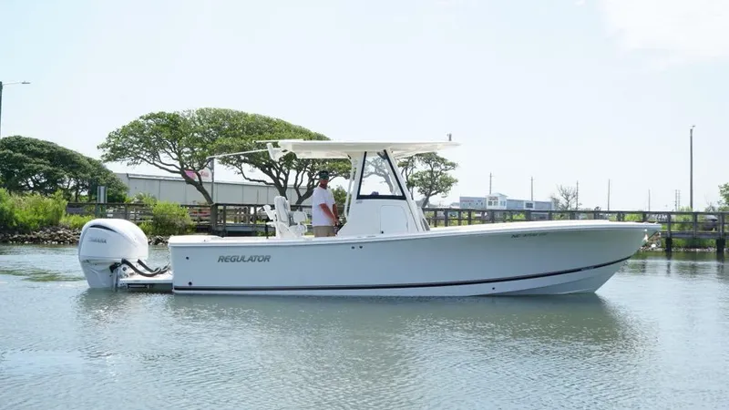 Slide: The Image of 2023 Regulator 28 boat on calm water, side view with trees in the background. - 3