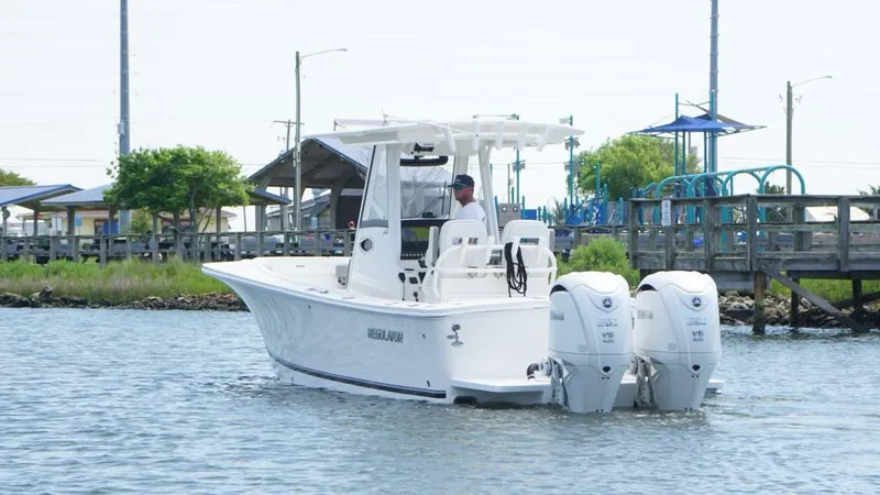 Slide: The Image of 2023 Regulator 28 boat with dual engines on a calm waterway near a dock. - 7