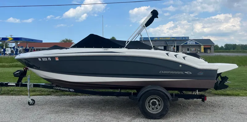 Slide: The Image of 2017 Chaparral 19 H20 Sport boat on trailer, parked outdoors under a blue sky. - 2