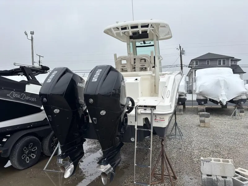 Slide: The Image of 2019 Boston Whaler 250 Outrage with dual Mercury outboard engines, parked on gravel. - 8