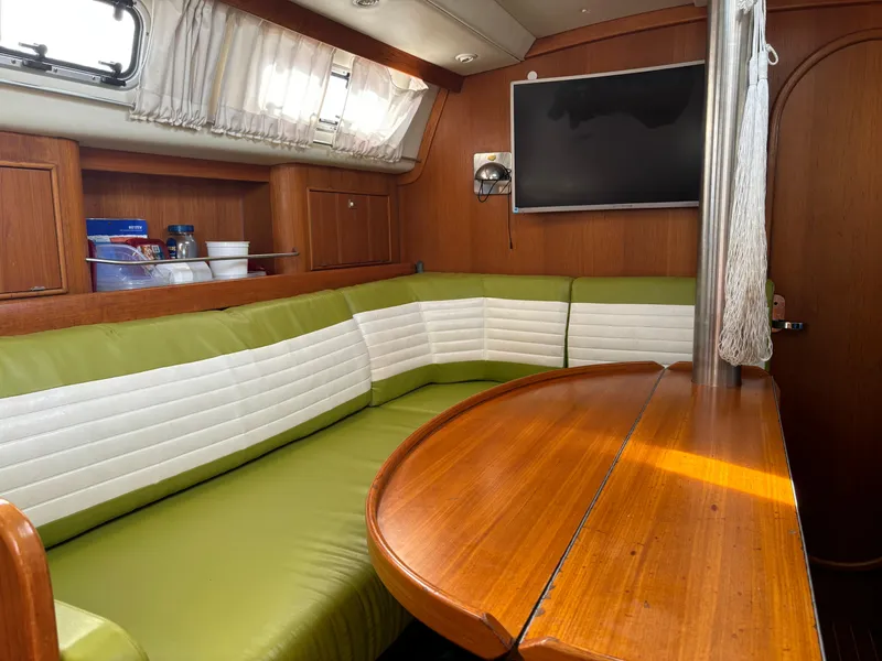 Slide: The Image of Cozy interior of 2001 Dragonfly 1200 sailboat with green seating and wooden table. - 19