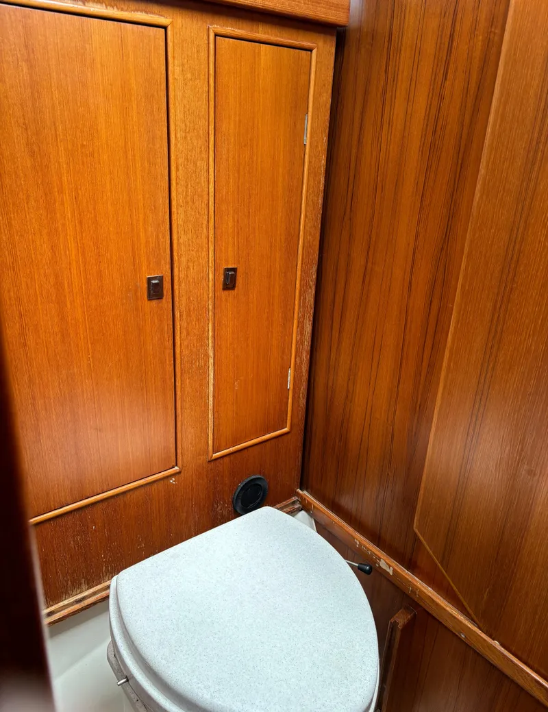Slide: The Image of Wood-paneled bathroom interior of a 2001 Dragonfly 1200 boat, featuring a compact toilet. - 24