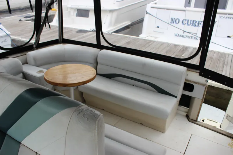 Slide: The Image of 1988 Sea Ray 340 Sundancer interior with cushioned seating and wooden table at dock. - 10