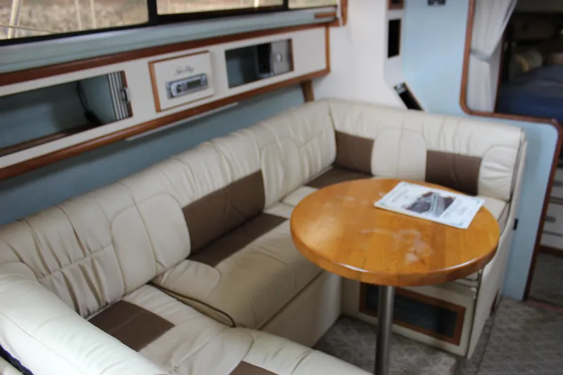 Slide: The Image of 1988 Sea Ray 340 Sundancer interior with beige seating and wooden table. - 18