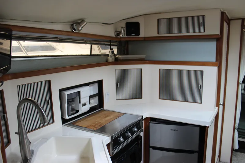 Slide: The Image of 1988 Sea Ray 340 Sundancer kitchen with stove, fridge, and sink. - 22