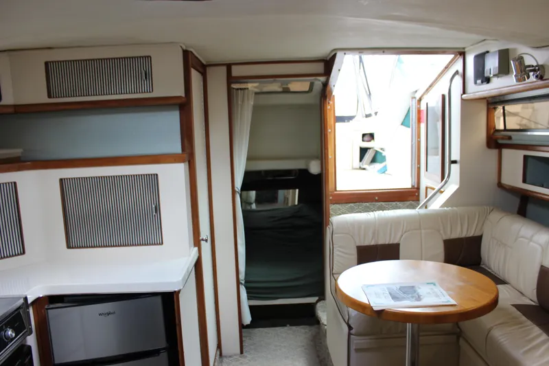 Slide: The Image of Interior of 1988 Sea Ray 340 Sundancer with seating, table, and compact kitchen area. - 23