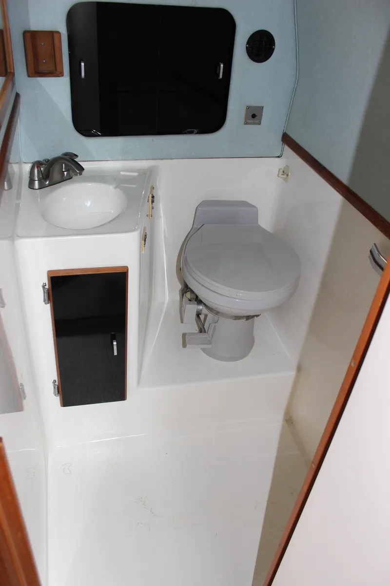 Slide: The Image of 1988 Sea Ray 340 Sundancer bathroom with sink, toilet, and storage cabinet. - 27