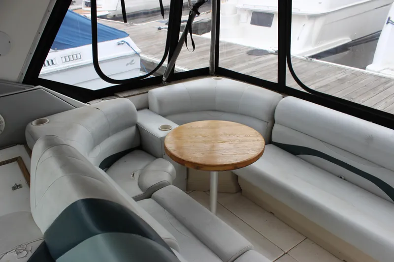 Slide: The Image of 1988 Sea Ray 340 Sundancer interior with curved seating and wooden table. - 31