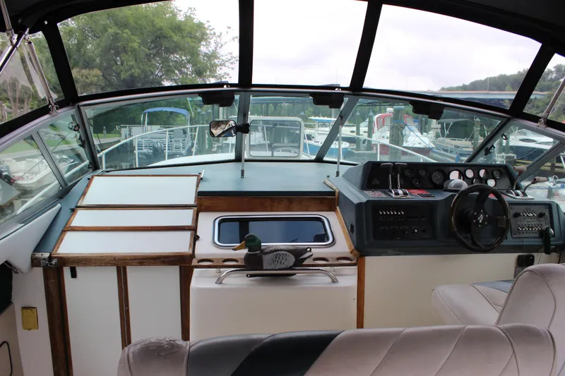 Slide: The Image of 1988 Sea Ray 340 Sundancer helm with steering wheel and control panel, docked at marina. - 7