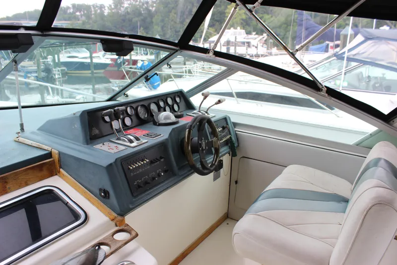 Slide: The Image of 1988 Sea Ray 340 Sundancer helm with gauges, steering wheel, and marina view. - 8