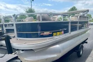 Slide: The Image of 2023 Sun Tracker Bass Buggy 16 XL pontoon boat on trailer, parked outdoors. - 6