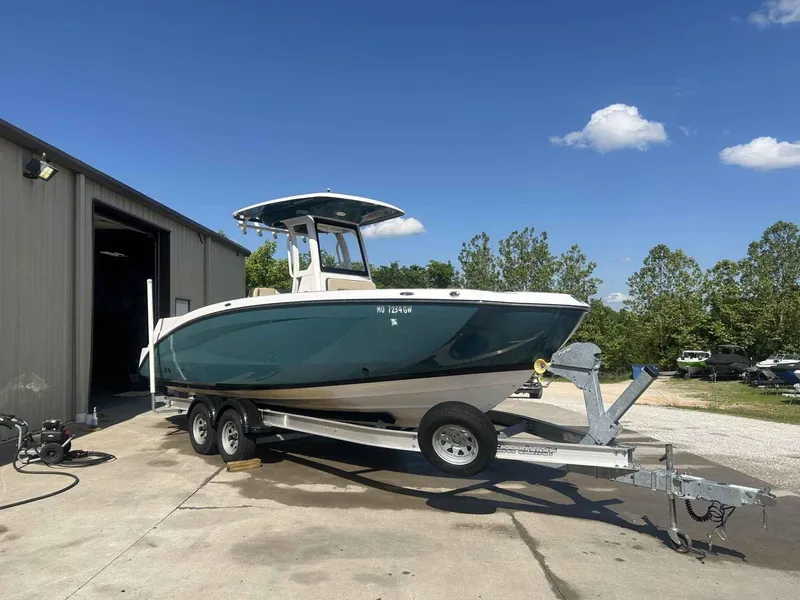 Slide: The Image of 2021 Yamaha Boats 255 FSH Sport E on trailer, parked outside a garage under clear sky. - 2