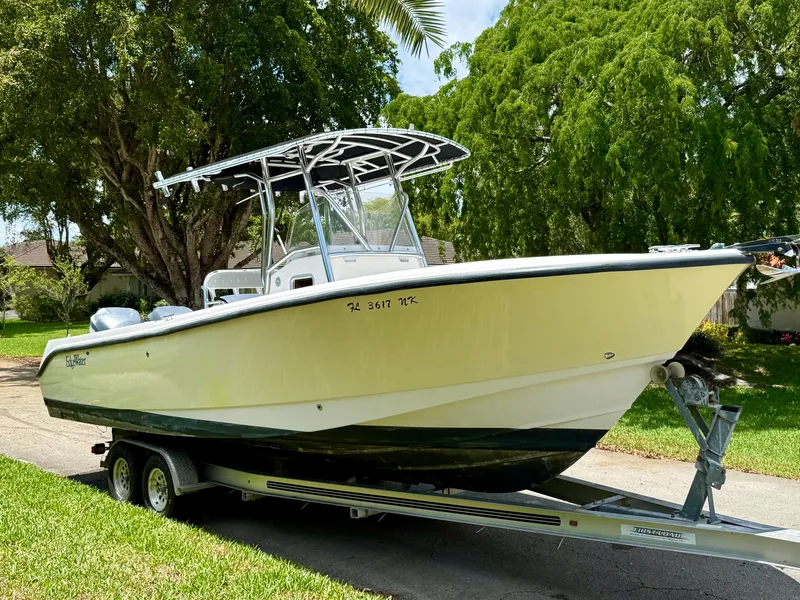 Slide: The Image of 2006 Edgewater 265CC boat on trailer, parked outdoors, surrounded by lush greenery. - 5