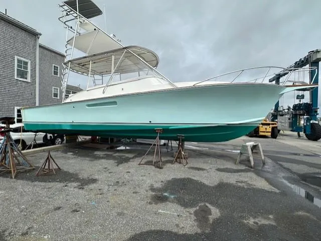 Slide: The Image of 2004 Stolper 38 boat on stands, light blue hull, overcast sky background. - 30