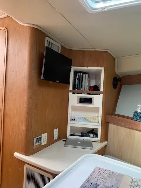Slide: The Image of Interior of a 2004 Stolper 38 boat with a TV, shelves, and a laptop. - 8