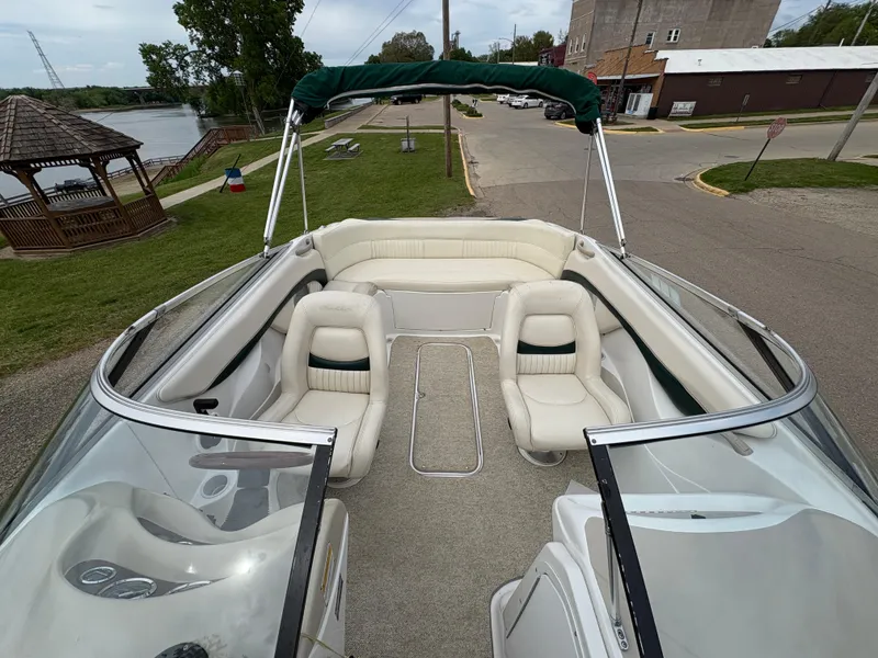 Slide: The Image of 1999 Chris-Craft 210 Bowrider with white seating, green canopy, parked near a riverside gazebo. - 14