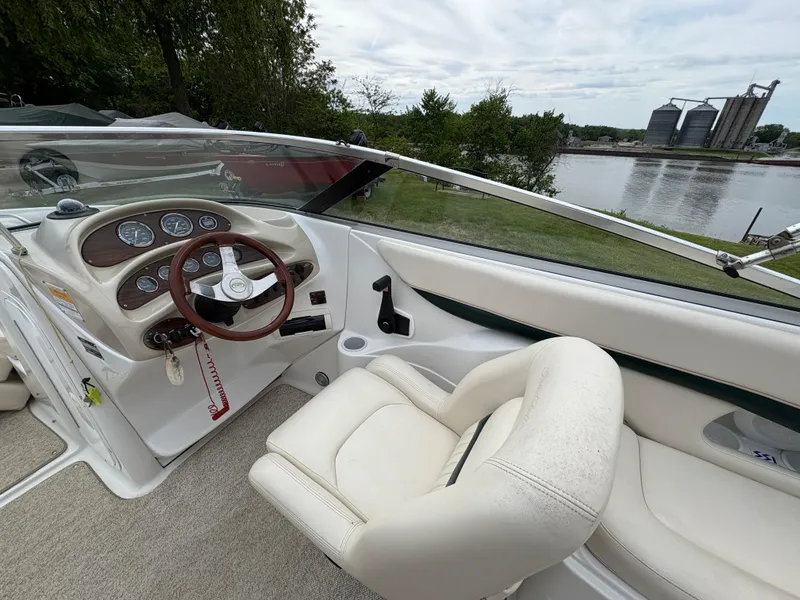 Slide: The Image of 1999 Chris-Craft 210 Bowrider interior with steering wheel, dashboard, and seating by a river. - 19
