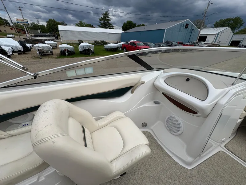Slide: The Image of 1999 Chris-Craft 210 Bowrider interior with white seating and dashboard, under cloudy skies. - 21