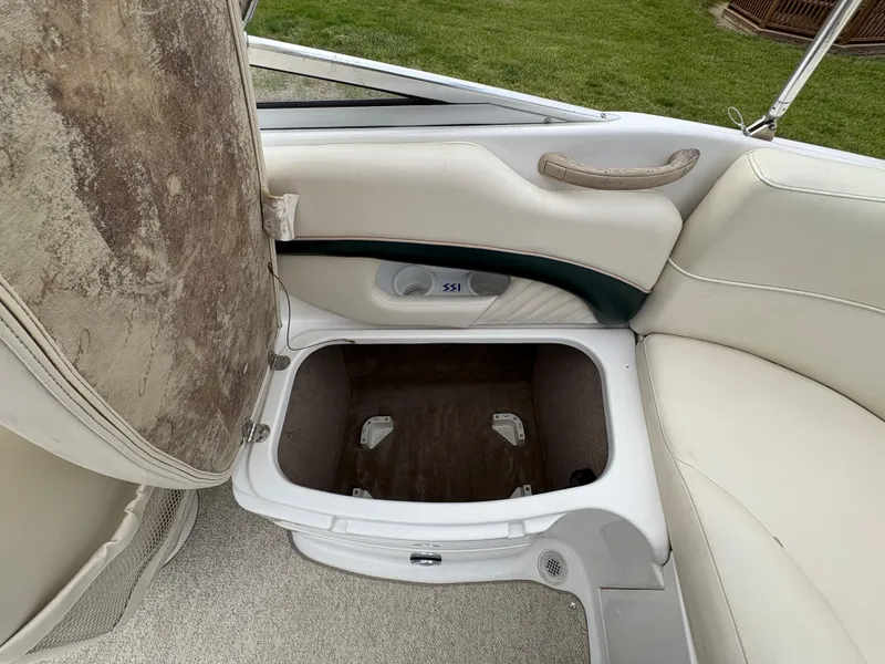Slide: The Image of 1999 Chris-Craft 210 Bowrider interior storage compartment with beige seating and carpet. - 24