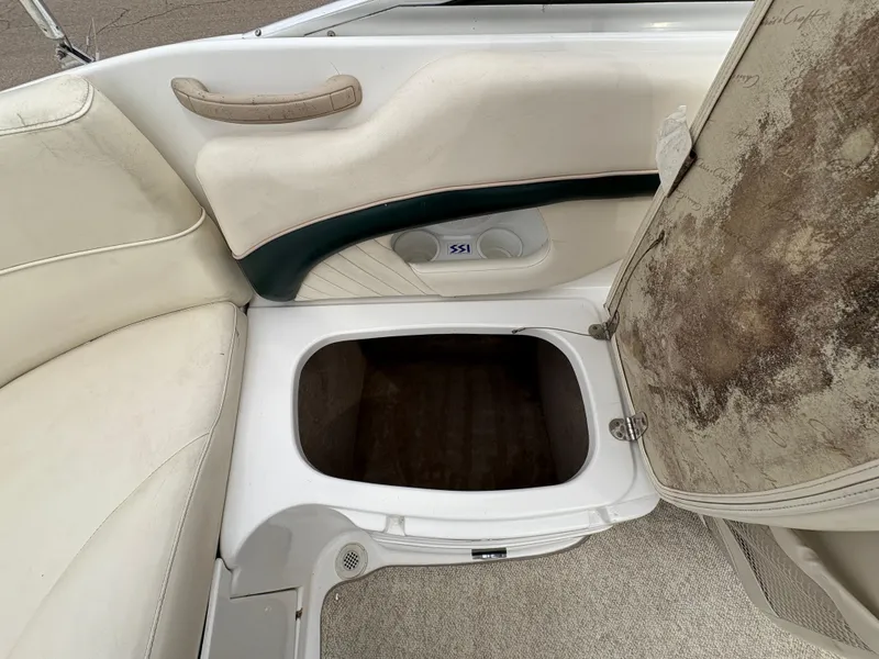 Slide: The Image of 1999 Chris-Craft 210 Bowrider interior storage compartment with open seat and visible wear. - 25