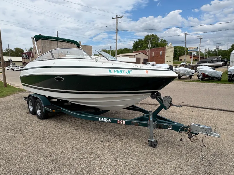 Slide: The Image of 1999 Chris-Craft 210 Bowrider on trailer, parked outdoors under a partly cloudy sky. - 3