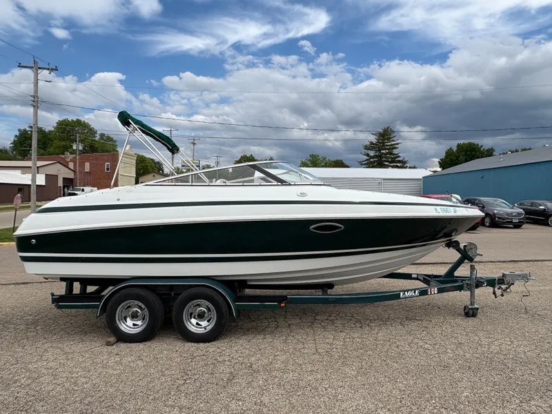 Slide: The Image of 1999 Chris-Craft 210 Bowrider on trailer, parked outdoors under cloudy sky. - 4