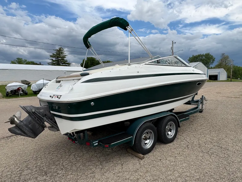 Slide: The Image of 1999 Chris-Craft 210 Bowrider on trailer, parked outdoors under cloudy sky. - 5