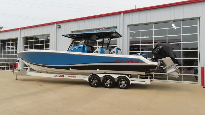Slide: The Image of 2023 Nor-Tech 390 Sport Center Console boat on trailer, parked outside a garage. - 1