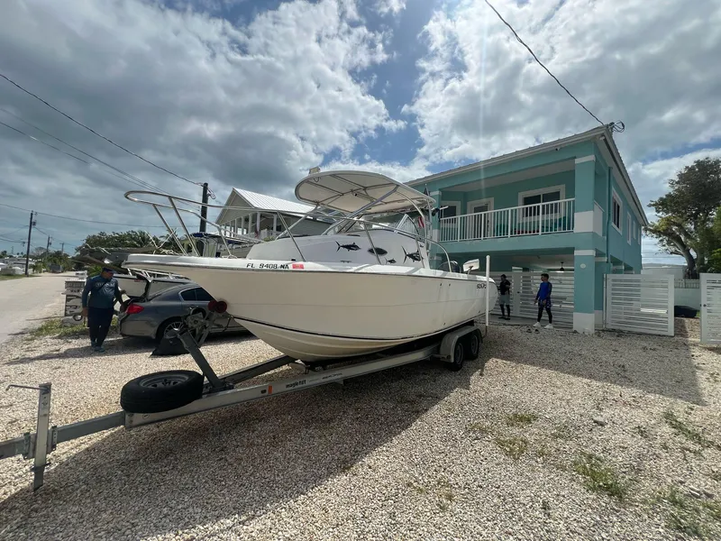 Slide: The Image of 2006 Sea Fox 257 Walk Around boat on trailer near a coastal house. - 3