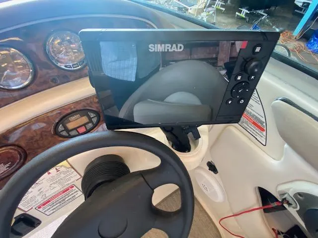 Slide: The Image of 2004 Sea Ray 240 Sundeck dashboard with Simrad navigation system and steering wheel. - 16
