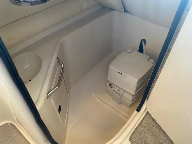 Slide: The Image of 2004 Sea Ray 240 Sundeck interior with portable toilet and sink. - 17