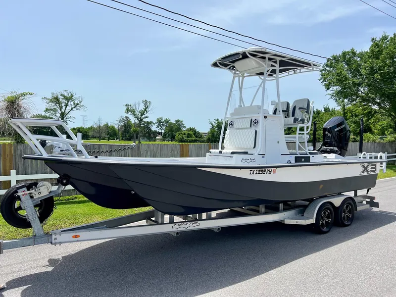Slide: The Image of 2024 Shallow Sport 25 X3 boat on trailer, parked on a sunny street. - 1