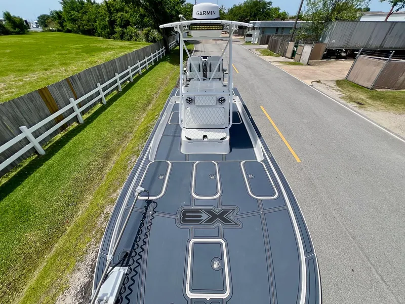 Slide: The Image of 2024 Shallow Sport 25 X3 boat on road, top view, near green field and fence. - 16