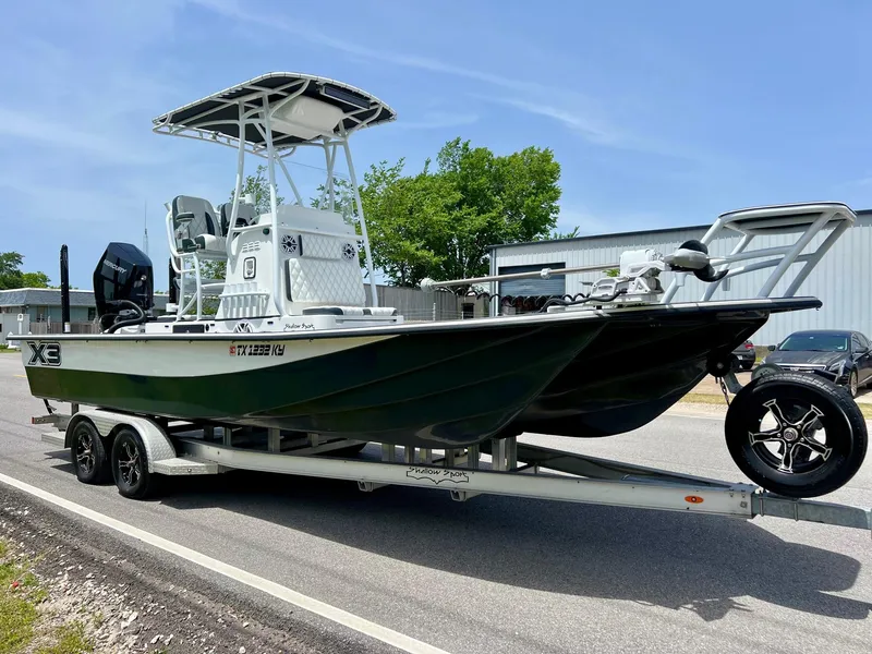 Slide: The Image of 2024 Shallow Sport 25 X3 boat on trailer, parked outdoors, with clear sky background. - 5