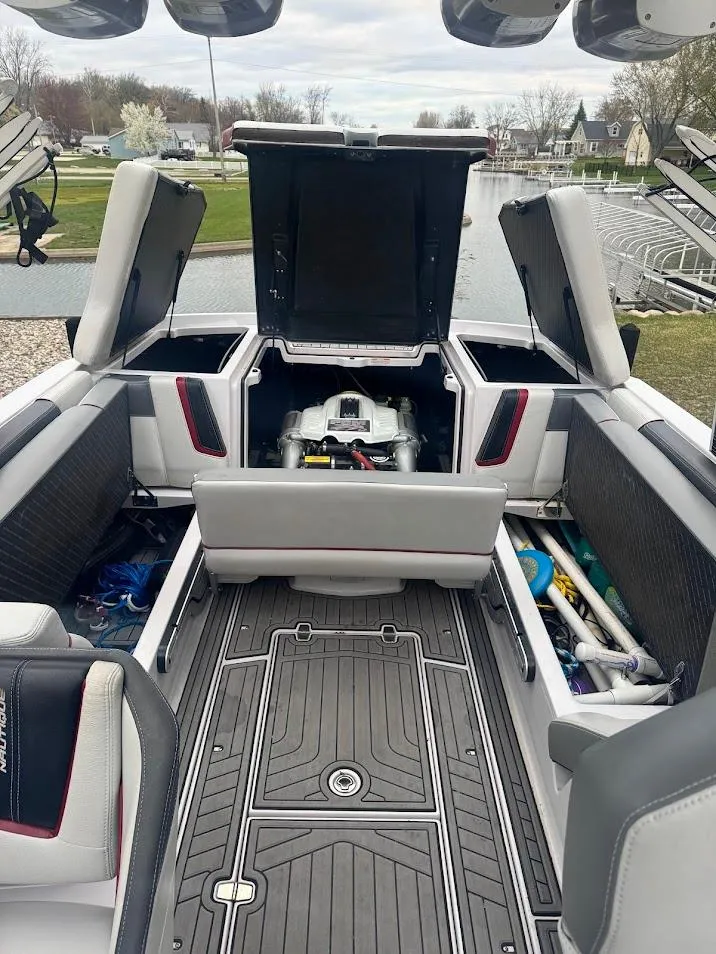 Slide: The Image of 2013 Nautique Super Air G23 interior with open engine compartment, showcasing storage and seating. - 18