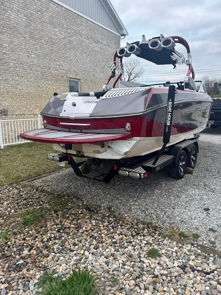 Slide: The Image of 2013 Nautique Super Air G23 boat on trailer, red and white design, parked on gravel. - 9
