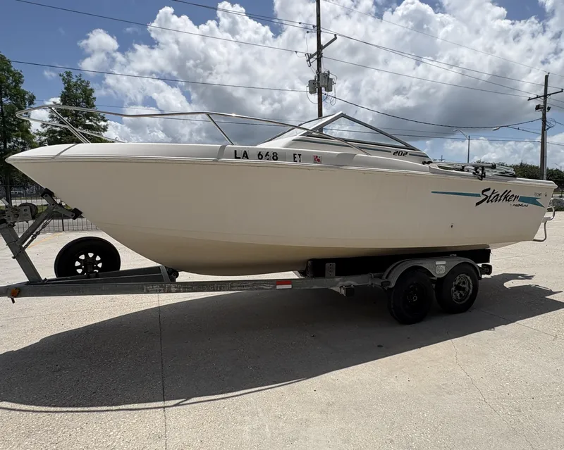 Slide: The Image of 1996 Pro-Line 202 Stalker boat on trailer, featuring an outboard motor, under a partly cloudy sky. - 3