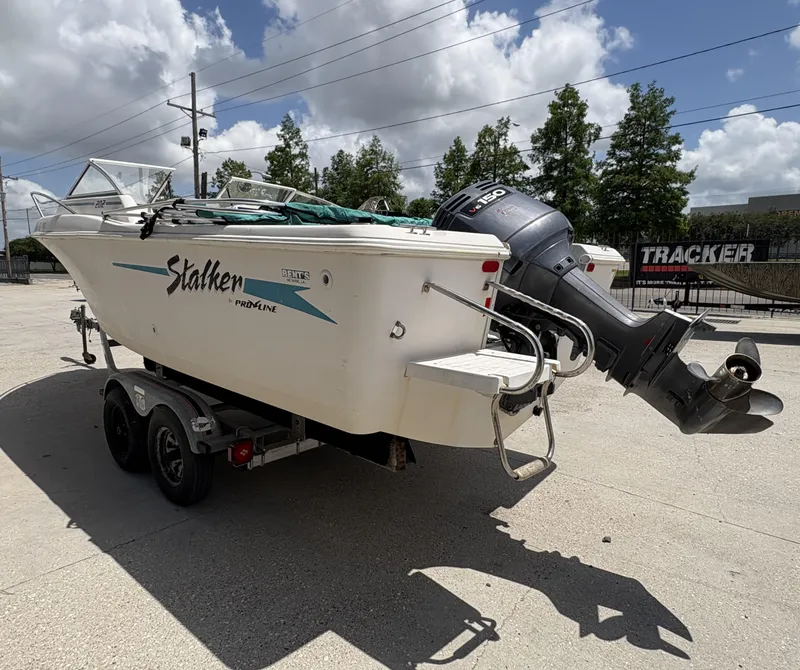Slide: The Image of 1996 Pro-Line 202 boat with outboard motor, docked under cloudy sky. - 4