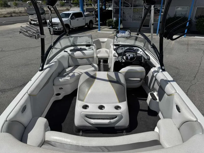 Slide: The Image of 2006 Tigé 21i boat interior with white seating and dashboard, parked outdoors. - 11